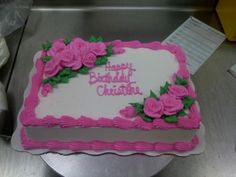 a pink and white birthday cake with roses on it