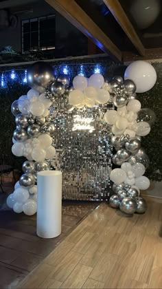 a large balloon arch with silver and white balloons