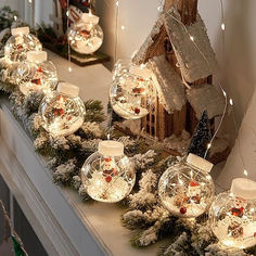 christmas decorations on a mantel with lights and snow globes in front of it