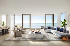 a living room filled with lots of furniture next to a large window overlooking the ocean