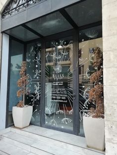 two large white planters sitting in front of a glass storefront with the words bliss written on it