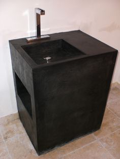 a black square sink sitting on top of a tiled floor