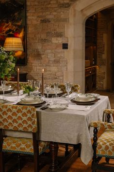 a dining room table is set with place settings and candles on the plates in front of it