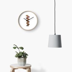 a clock that is on the wall next to a table with a potted plant