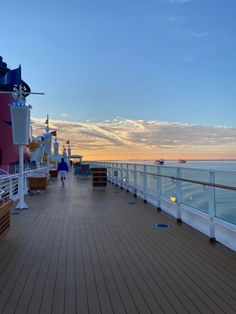 the deck of a cruise ship with people walking on it at sunset or sunrise time