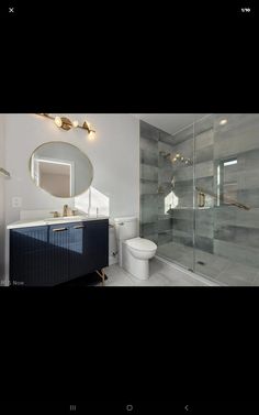 a bathroom with a sink, toilet and glass shower stall in front of the mirror