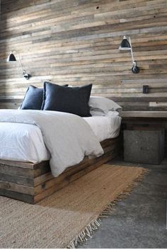 a large bed sitting next to a window in a bedroom under a wooden headboard