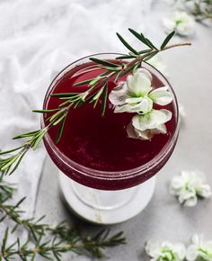 a close up of a drink in a glass with flowers on the rim and text that reads rosemary bourbon and casses