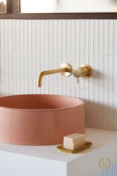 a bathroom sink with a gold faucet and pink bowl on the countertop