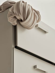 a white dresser with two drawers and a bow on top