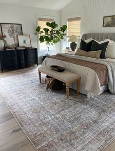 a bedroom with a large bed and rugs on the floor in front of it