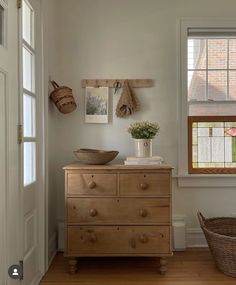 a wooden dresser sitting in front of a window next to a basket on top of it