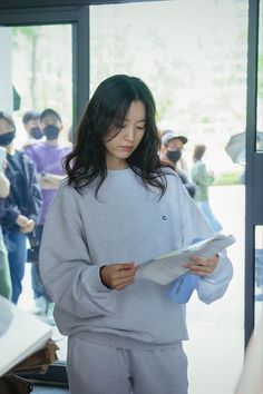 a woman standing in front of a group of people holding papers and looking at something