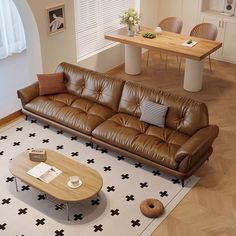 a brown leather couch sitting in a living room next to a wooden table and chairs