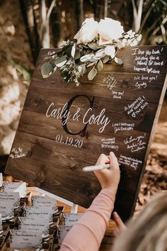 a person writing on a wooden sign at a wedding