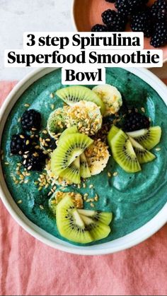 a bowl filled with green smoothie topped with kiwis and blackberries next to a bowl of berries