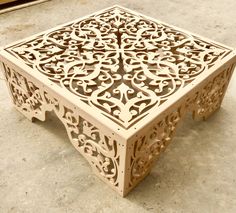 an intricately carved wooden table sits on the ground