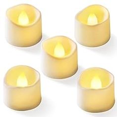 four white candles with yellow wax in the middle and one light on each candle is lit