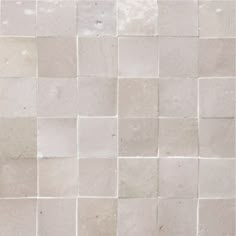 a white tile wall that has been made up of several different sized and shaped tiles