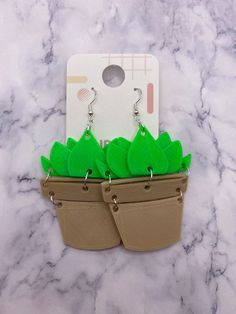 two plant shaped earrings sitting on top of a table