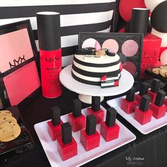 a black and white table topped with cakes and desserts covered in pink and red icing