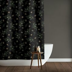 a white toilet sitting next to a bath tub under a black shower curtain with green leaves on it