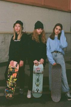 three girls standing next to each other holding skateboards