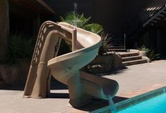 a water slide sitting in the middle of a swimming pool next to a building with stairs