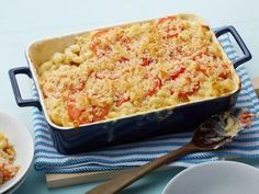 a blue casserole dish filled with macaroni and cheese next to two plates