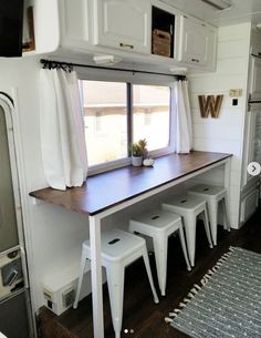 the interior of a mobile home with white stools and a table in front of it