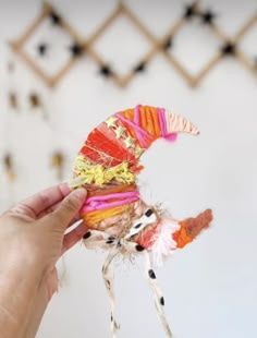 a person is holding up a colorful bird ornament with feathers and feathers on it