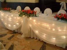 the table is set with white cloths and red flowers