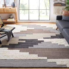 a living room with a couch, chair and rug on the floor in front of a large window