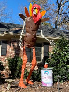 a large inflatable turkey standing next to a can of canned orange juice on a yard