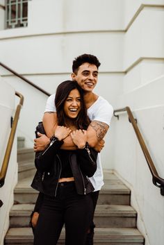 a man and woman are hugging on the stairs