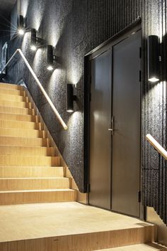 a set of stairs leading up to a door with lights on each side and another light above them