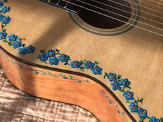 an acoustic guitar with blue flowers painted on it's body and fret cover