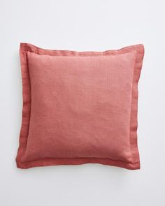 an orange pillow on a white surface with a pink linen back droplet and contrasting edges