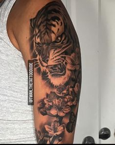 a man with a tiger and flowers tattoo on his arm is standing in front of a mirror