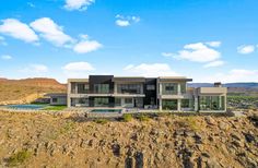 an aerial view of a modern home in the desert with pool and mountains behind it