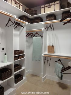 a walk in closet filled with lots of white shelves and brown baskets on top of them