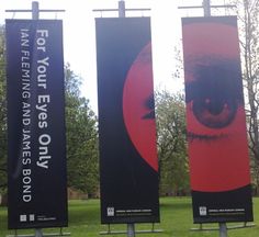 three black and red banners on poles in the grass