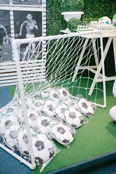 soccer balls sitting in front of a net on display at a sports themed birthday party