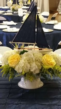 a vase filled with white and yellow flowers on top of a blue cloth covered table