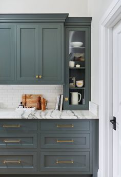 a kitchen with gray cabinets and marble counter tops