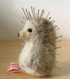 a stuffed hedgehog sitting on top of a table next to a pile of pins