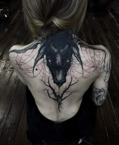 the back of a woman's body with tattoos on it and an image of a bird