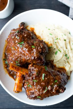 a white plate topped with meat and mashed potatoes