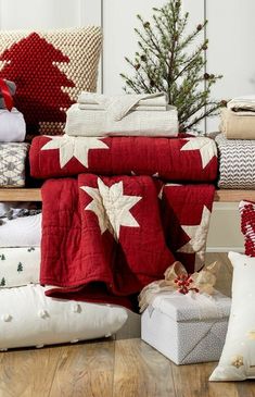 a pile of red and white blankets sitting on top of a wooden floor next to a christmas tree