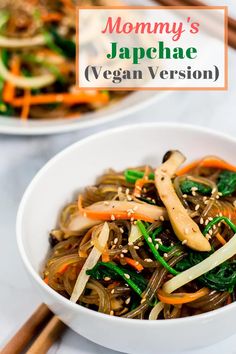 a bowl filled with noodles and vegetables next to chopsticks on a table top